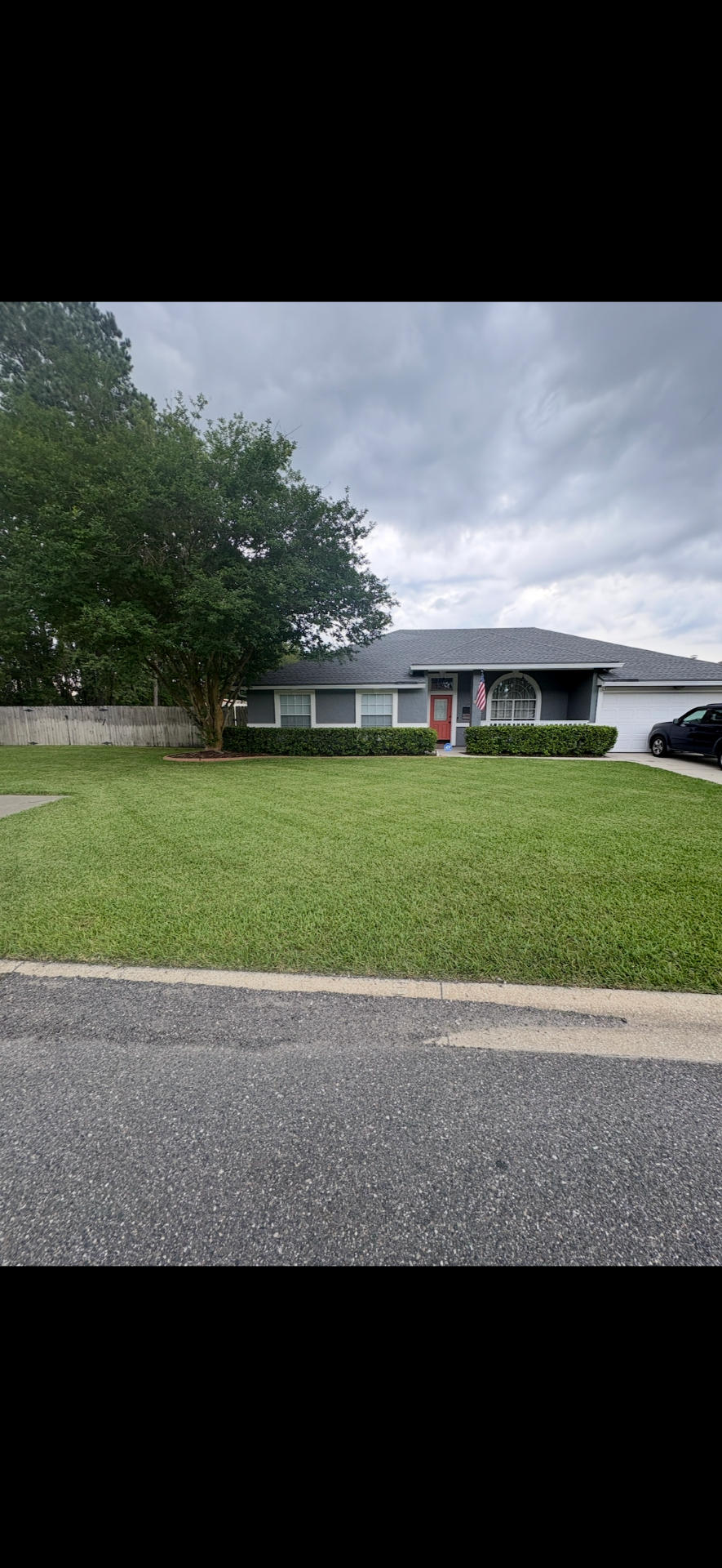 Freshly mowed front lawn at a gray ranch home with American flag