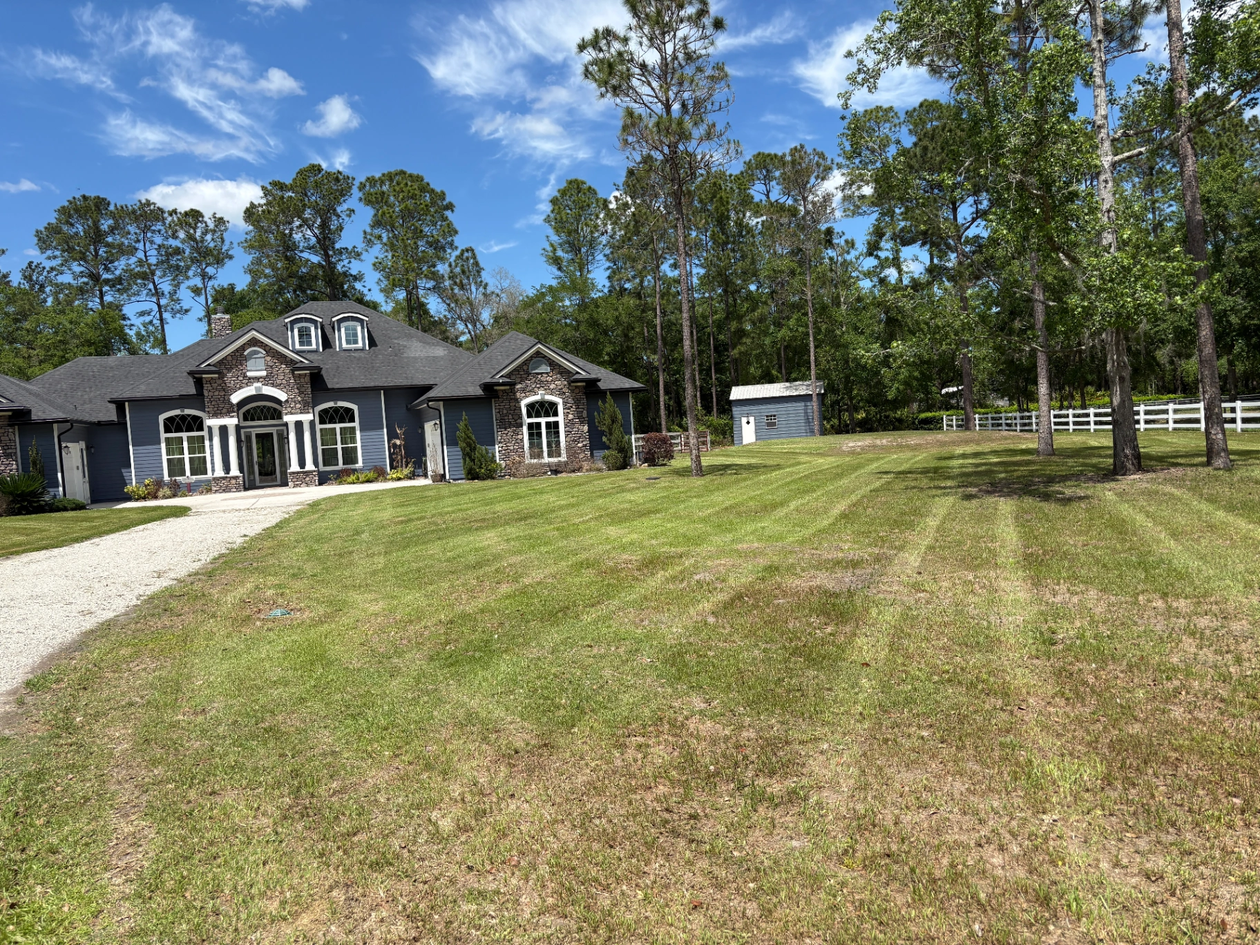 Striped lawn mowing on a large estate with stone-accented home